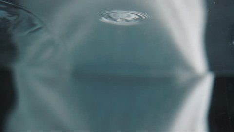 slow motion of a woman washing and caressing her face underwater. camera underwater in a pool shooting a model washing her face