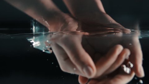 woman splashing her hands in a pool in slow motion, slow motion girl submerging her hands in a basin