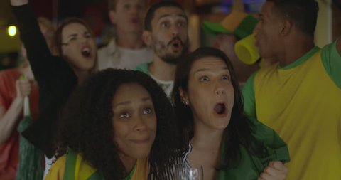 Brazilian football fans celebrating victory in sports bar, slow motion
