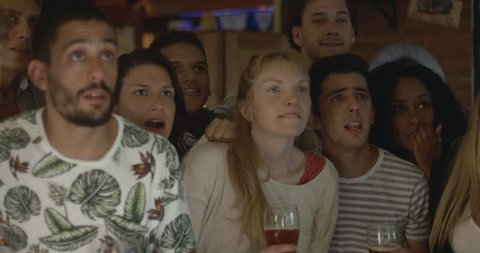 Sports enthusiasts celebrating victory while watching televised match in bar, slow motion