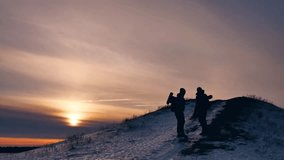 people winter silhouette snow sunlight. group of tourists walking on top of a sunset silhouette mountain. slow video tourists people group go travel lifestyle nature