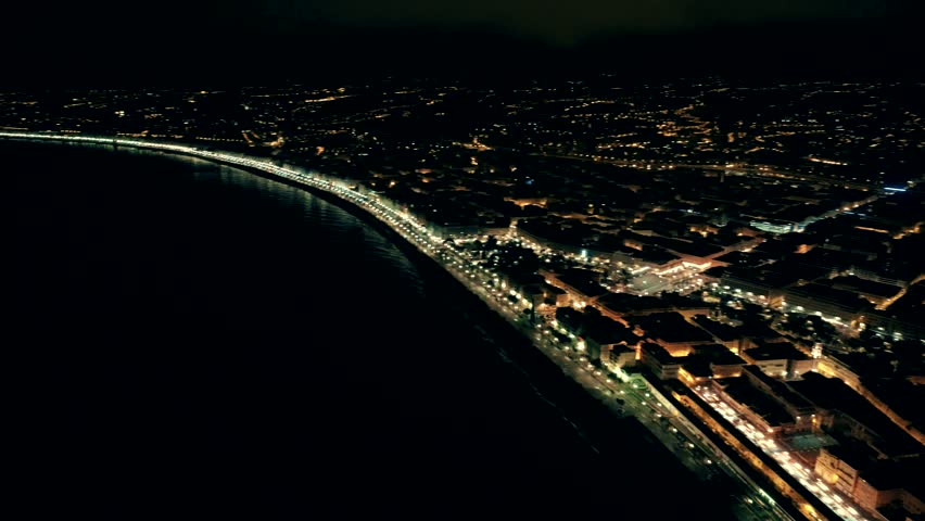 Night aerial view of sea and illuminated Nice town in France. Flight over promenade.