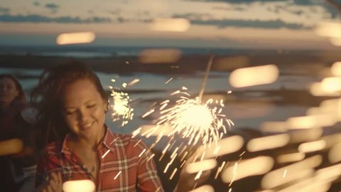 Attractive young woman is dancing with sparkler at evening, slow motion