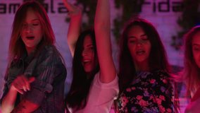 Attractive girls dance close together on dance floor friends at party on the background of disco lights