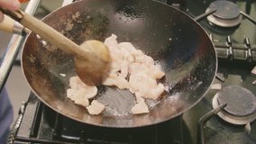 Man Sauteing Sizzling Chicken Meat In Wok