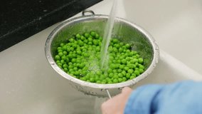 Man Washing Fresh Green Peas In Colander At Kitchen
