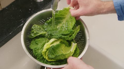 Closeup Shot Of Man Washing Savoy Cabbage Leaves In Colander