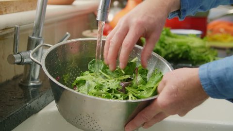 Closeup Of Man Hands Washing Green Leafy Vegetable In Colander