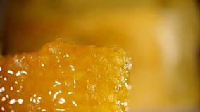 Honey dripping from honey dipper on honeycomb, over yellow background. Thick organic honey dipping from the wooden honey spoon