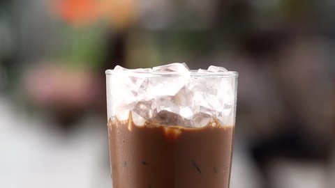 close up pouring milk to glass of ice coffee