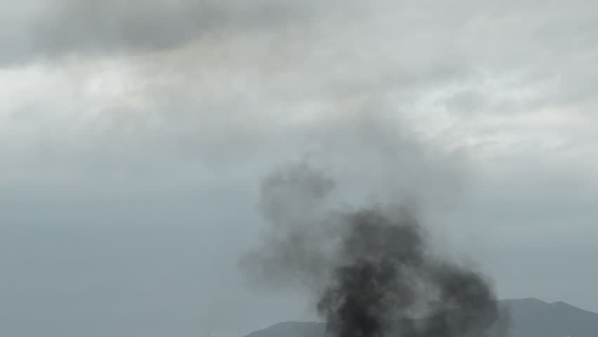 Big column of black smoke from a fire going up in the sky
