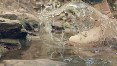 Boot splashing in water puddle (slow motion)