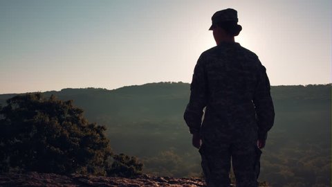 Soldier looking out over mountains at sunrise