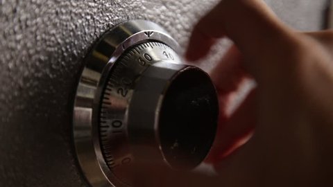 Locking and then opening a safe - close up on dial - combination lock of a safe or vintage bank steel vault used by a person or bank teller or robber breaking in and stealing money and jewelry 