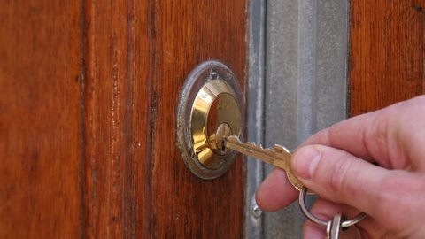 Using a key to open the lock of the front door.