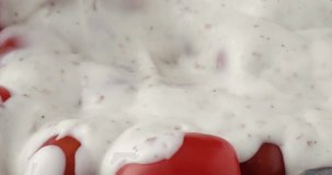 Close video of mixing ranch dressing into ripe grape tomatoes then taking two with a fork.