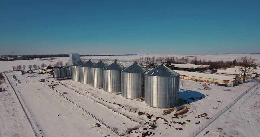 Agriculture industry, manufacturing plant . Agriculture grain silos storage tank. Modern large granary. Large metal silos. Elevator and factory. Winter Sunny day, the blue sky