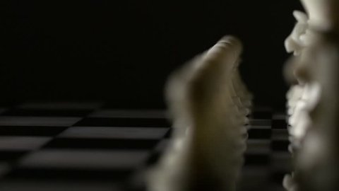 Tracking shot of ivory chess pieces on a marble chess board
