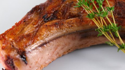 Close-up view of grilled pork chop, decorated with thymus vulgaris, served in Restaurant, loop, 4K, ProRes source codec