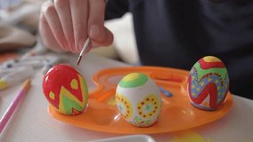 Man paints the Easter eggs. Easter painting.Man decorating colorful eggs.Colored Easter eggs in the basket