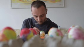Man paints the Easter eggs. Easter painting.Man decorating colorful eggs.Colored Easter eggs in the basket
