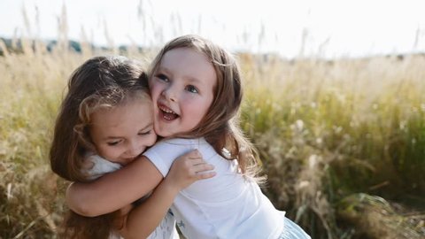 Two smiling, curly, cute baby-girls hug tightly each other. True friendship, friends for ages. Playing, happy childhood, positive emotions, true feelings