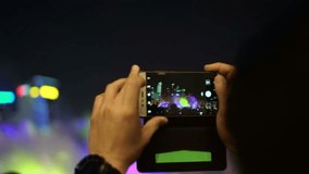 Hands using smartphone record, take photo colourful show