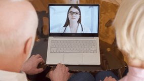 Top view of senior couple at home having medical consultation video chat on laptop with physician. Confident professional female doctor with stethoscope talking with patients via messenger app call