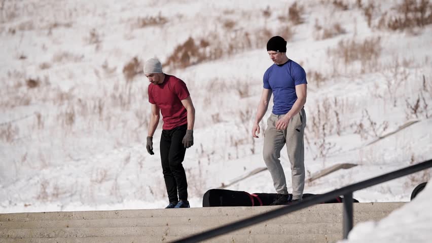 Two athletic man going downstairs doing a handstand outdoor in winter.