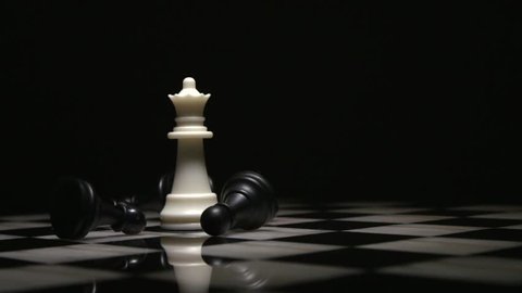 chess queen piece surrounded by fallen black pawns