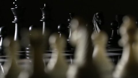 Slow tracking shot behind chess pieces on marble chess board
