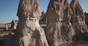Advancing aerial drone footage flying between fairy chimneys revealing many cave houses carved into hoodoo mountain above Rose Valley and Cappadocia nature landscape in Goreme, Turkey. 4k at 23.97fps