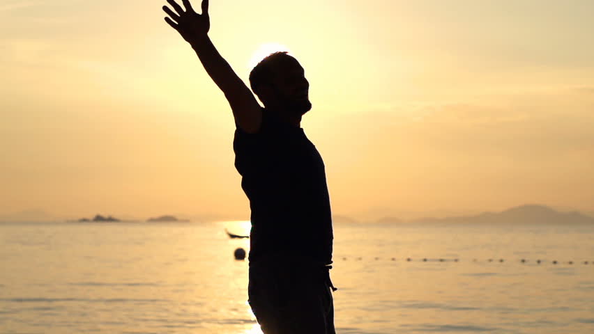 Silhouette of happy man turning around on beach during sunset, super slow motion 240fps
