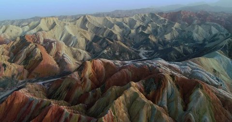 Flying drone over Rainbow mountains. Aerial view on most beautiful section of Zhangye Danxia Rainbow Mountains showing hills covered with multicolored pattern.