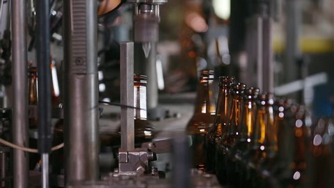 Electronics checks the quality of bottle on glass factory. Sorting beer bottles. Quality control of glass bottles. Technological line for bottling of beer in brewery. Beer bottle factory. Close up.