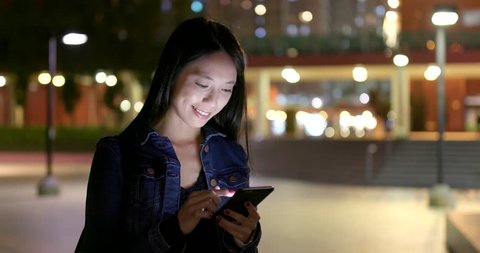Woman use of mobile phone for online at night in the city