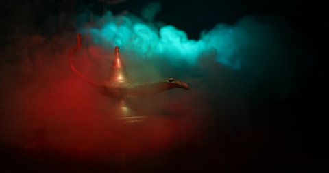 Slider shot.  Antique artisanal Arabian nights genie style oil lamp with soft light white smoke. dark smoky toned background. Lamp of wishes