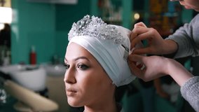 Woman tying islamic wedding turban for beautiful model