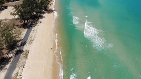 Tropical beach with aerial top view of green foaming ocean waves crushing against the coast line