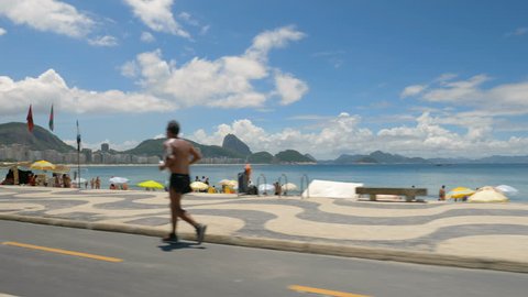 RIO DE JANEIRO, BRAZIL - FEBRUARY 2018 : Copacabana Beach on Sunny Day, Rio De Janeiro, Brazil. Driving along the famous mosaic walkway. Slow motion
