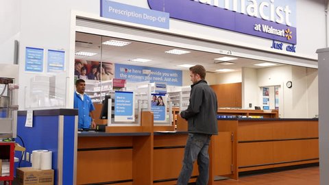 Port Coquitlam, BC, Canada - March 20, 2018 : Motion of man picking up his prescription medicine inside Walmart pharmacy section with 4k resolution