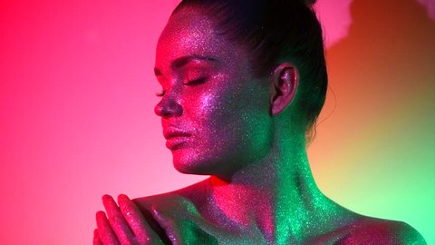 High Fashion model woman in colorful bright sparkles and neon lights posing in studio, portrait of beautiful sexy girl, trendy glowing make-up. Art design colorful Glitter Vivid makeup 4K slow motion Stock Video