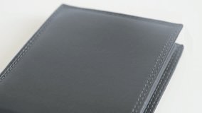 Bi-fold black money case front surface  3840X2160 UltraHD tilting footage - Leather wallet on white background  slow tilt 3840X2160 UHD video