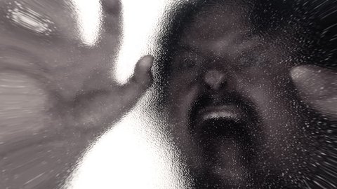 Lens distorted scene: a zombie lurking behind a frosted glass door and attacking the viewer. Horror Halloween themed shot.
