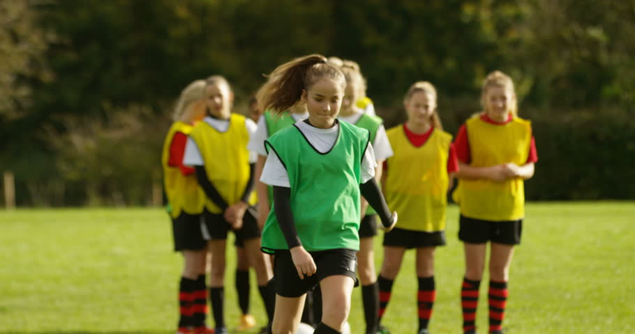 4K Young female soccer team practising ball control & dribbling on school sports field. Slow motion.