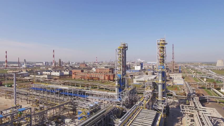 Giant petroleum engineering in rural areas on a summer sunny day with a clear blue sky. Red and white pipes, a huge territory among agricultural crops - Aerial view. Royalty-Free Stock Footage #1009005317
