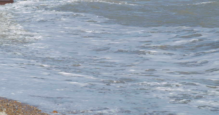 Close up of waves crashing onto the pebbles at eastbourne beach.