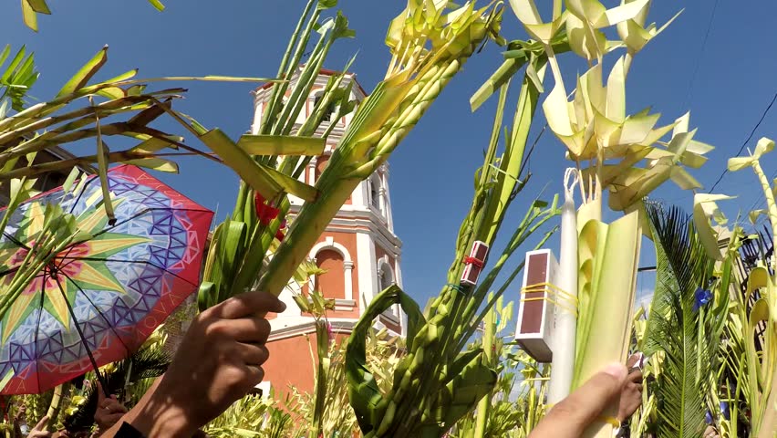 San Pablo City, Laguna, Philippines, March 25, 2018: Church tower background, Catholics waving coconut palm leaves on Palm Sunday. The feast commemorates Jesus' triumphal entry into Jerusalem, Royalty-Free Stock Footage #1009007123