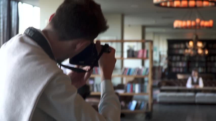 Photographer takes a photo of a groom in the hall of a restaurant.