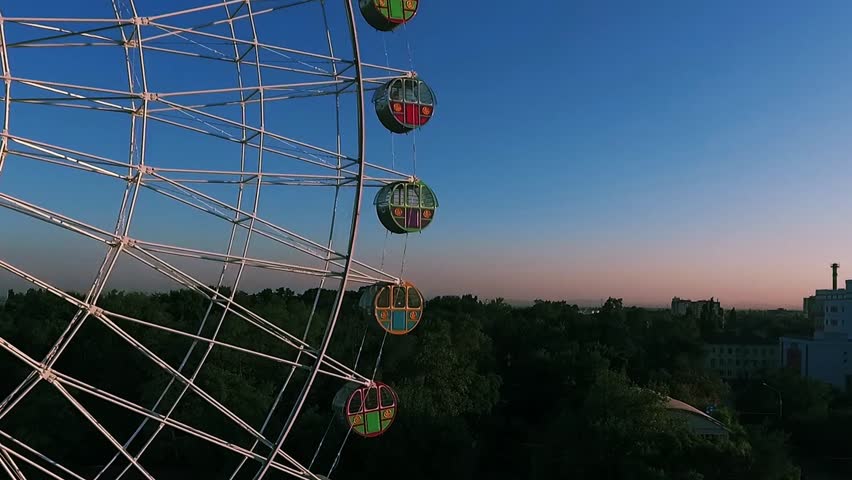 Ferris wheel. Blue sky. Green Forest